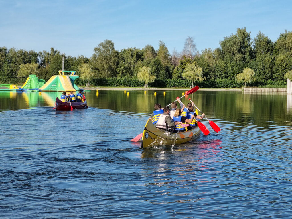 Een groep mensen die deelneemt aan teambuilding door middel van een reuzekano waar zij met z'n allen inzitten.