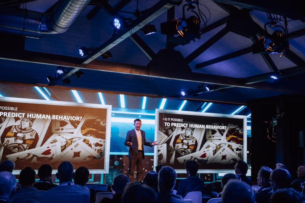 Congres bij Beachclub Degreez met spreker op het podium, groot scherm en professionele audiovisuele ondersteuning.