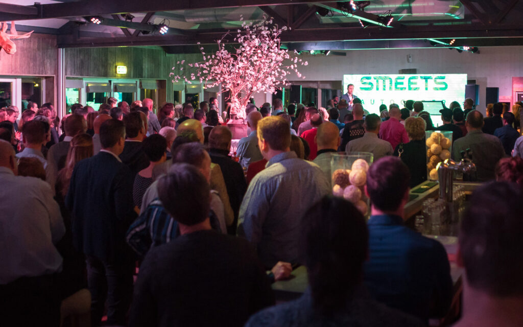 Mensen die luisteren naar een presentatie op een personeelsfeest van Smeets Autogroep.