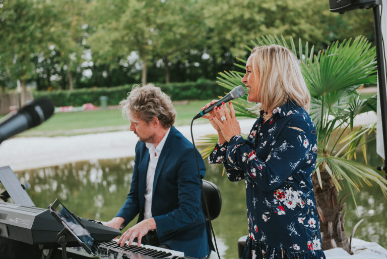 Zangeres en pianist verzorgen live muziek tijdens een bedrijfsjubileum bij Beachclub Degreez