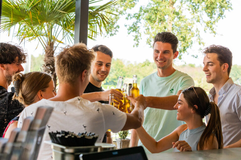 Collega's proosten met drankjes tijdens een personeelsfeest bij Beachclub Degreez.