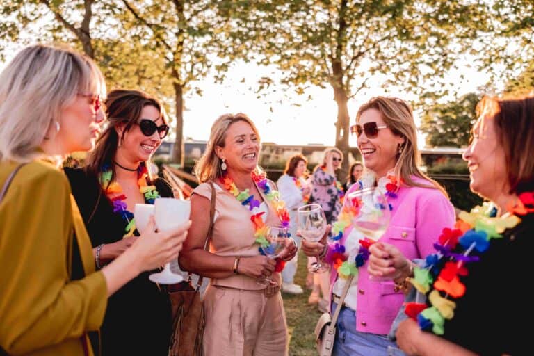 Vrouwen lachen en proosten tijdens een zomers feest bij Beachclub Degreez in LImburg.