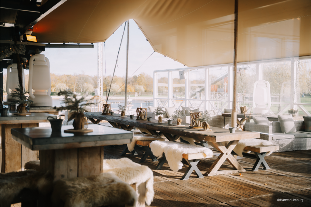 Het deels overdekte terras van Beachclub Degreez met lange tafels en uitzicht over het water.