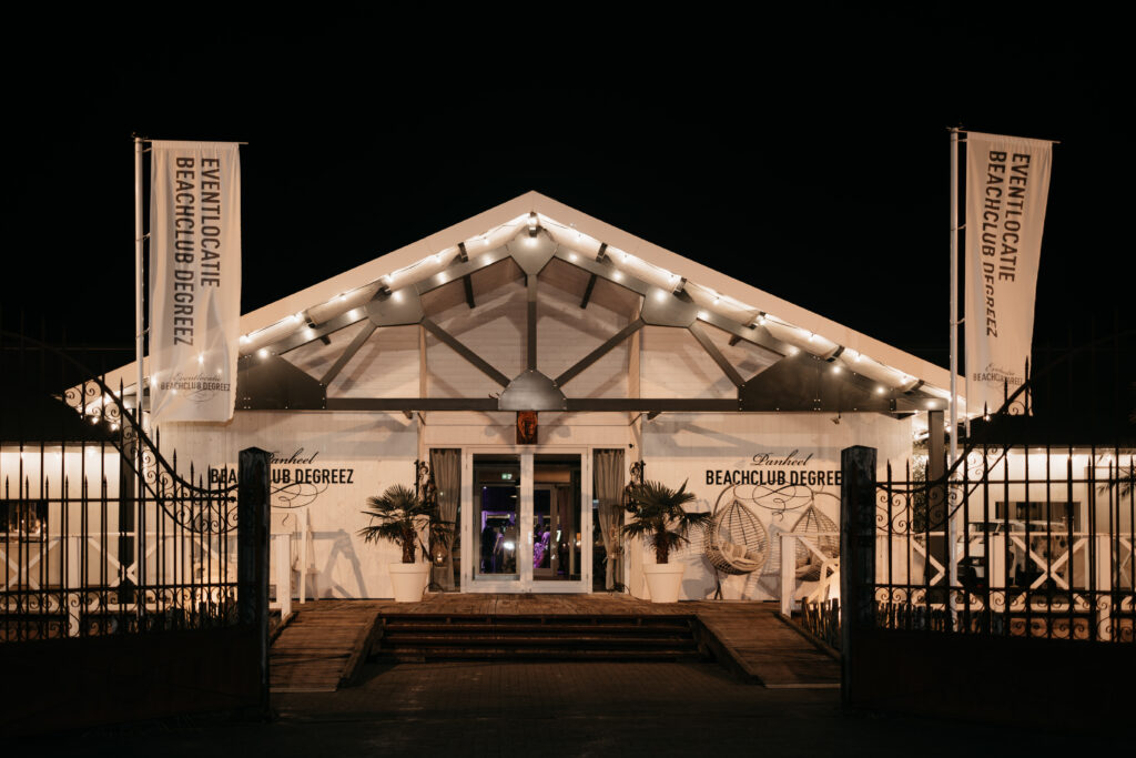 Verlichte entree van eventlocatie Beachclub Degreez in de avond, herkenbaar en uitnodigend voor gasten.